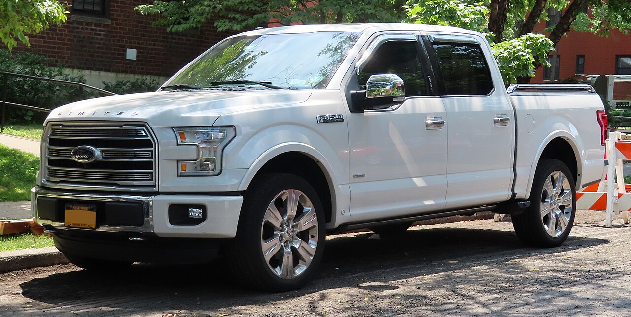 A white 2016 Ford F-150 Limited SuperCrew parked on a residential street, seen from the front right