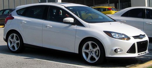 A white 2012 Ford Focus Titanium hatchback parked in a lot