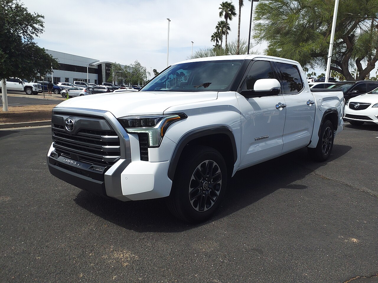 A white 2023 Toyota Tundra Limited CrewMax parked on a dealer lot, seen from the front left